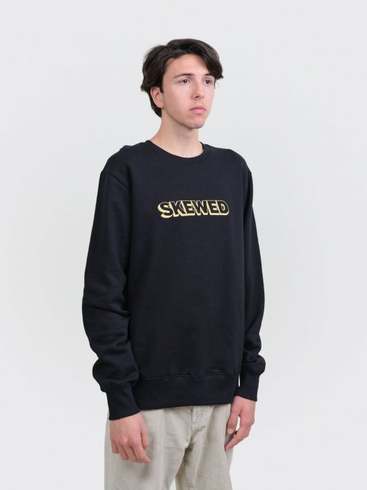 Model wearing unisex black sweatshirt with big skewed logo in gold colour
