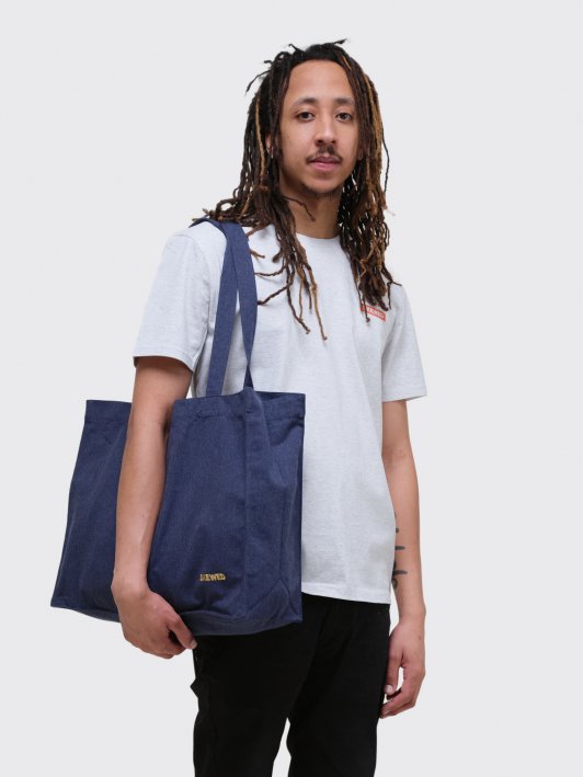 model wearing blue shopping bag with gold skewed logo